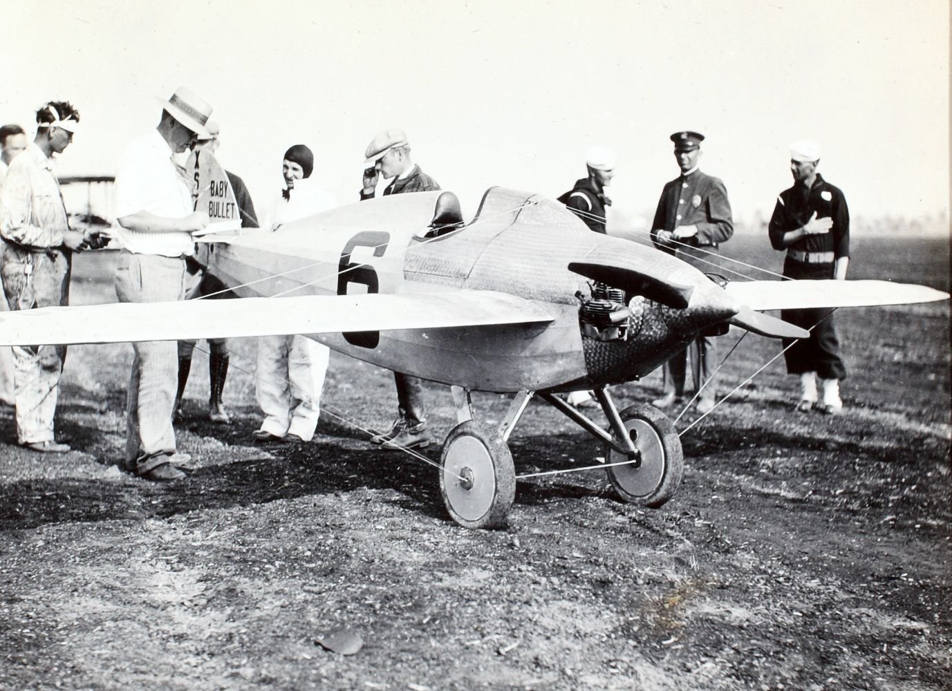 Figure 3 — The Heath Baby Bullet, race number 6, with officials and spectators. The midget racer was rebuilt after the 1928 fire at the Heath plant on Broadway in Chicago and won its class at the National Air…