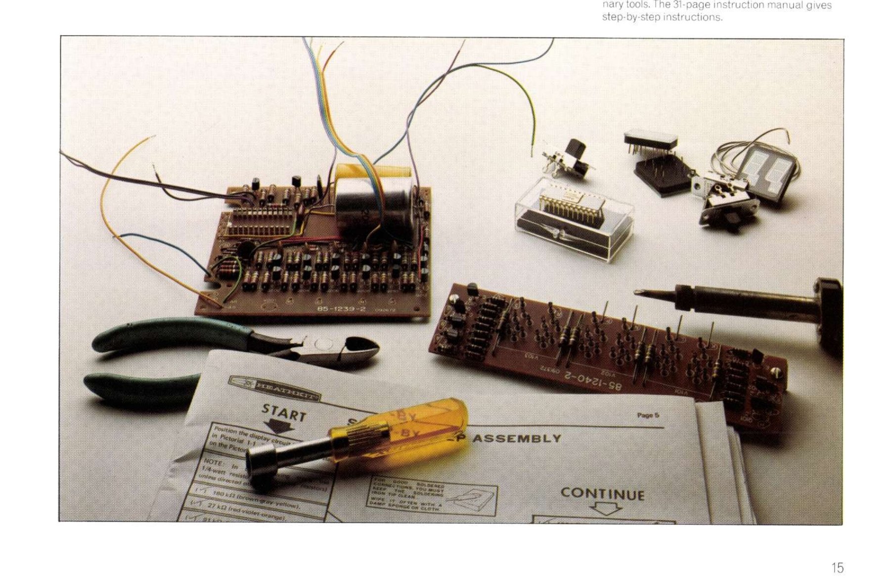 Figure 21 — The clock's two circuit boards "nearly complete after a few hours work with ordinary tools", with the step-by-step manual open at the START and CONTINUE pages. The report states that the whole cloc…