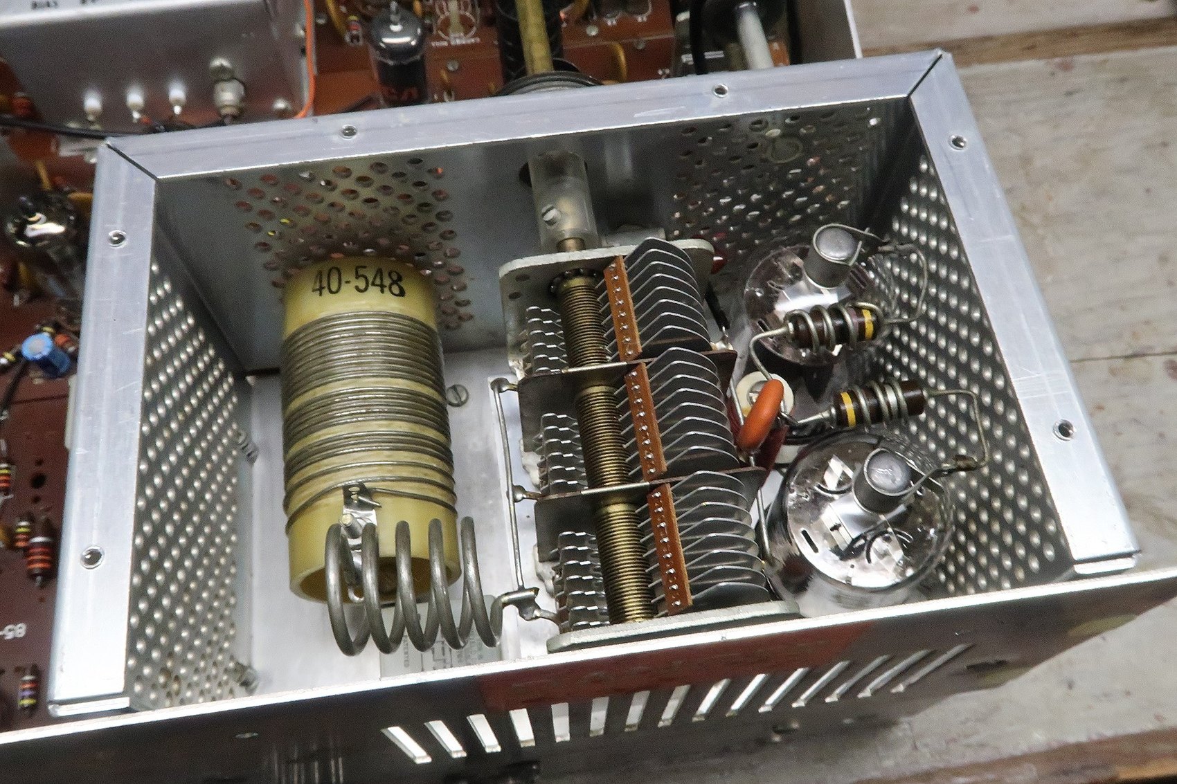Figure 9 — Inside the high-voltage cage: the two 6146 finals, the pi-network coil and the air-variable tuning and loading capacitors. The cage is both a shield and a safety barrier, and it runs hot — forced a…