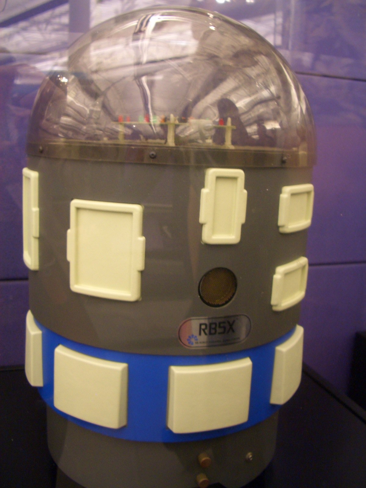 Figure 11 — An RB5X from RB Robot Corporation of Golden, Colorado, in a museum case. The transparent dome, the bumper panels and the sonar port are visible. RB Robot's president, Joe Bosworth, conceived the In…