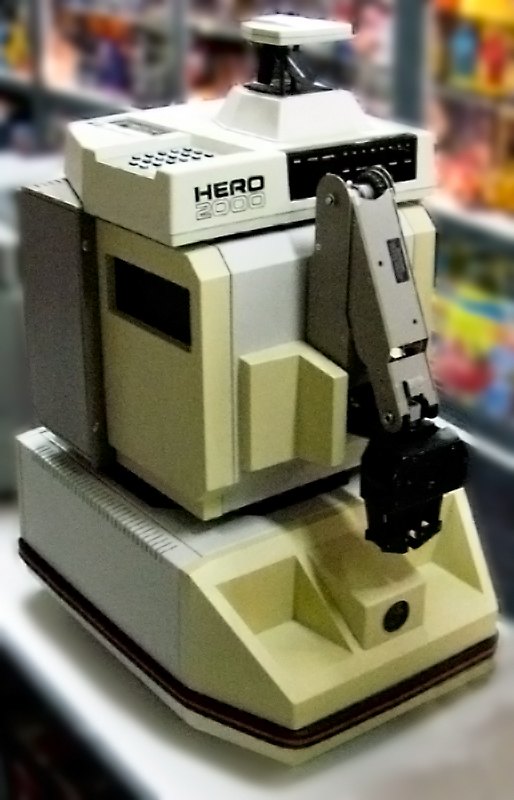Figure 11 — A surviving HERO 2000 with its arm. The head carries the keypad, the status LEDs and the sonar turret; the wide base holds the two side drive wheels and the 24 amp-hour battery. This photograph is …