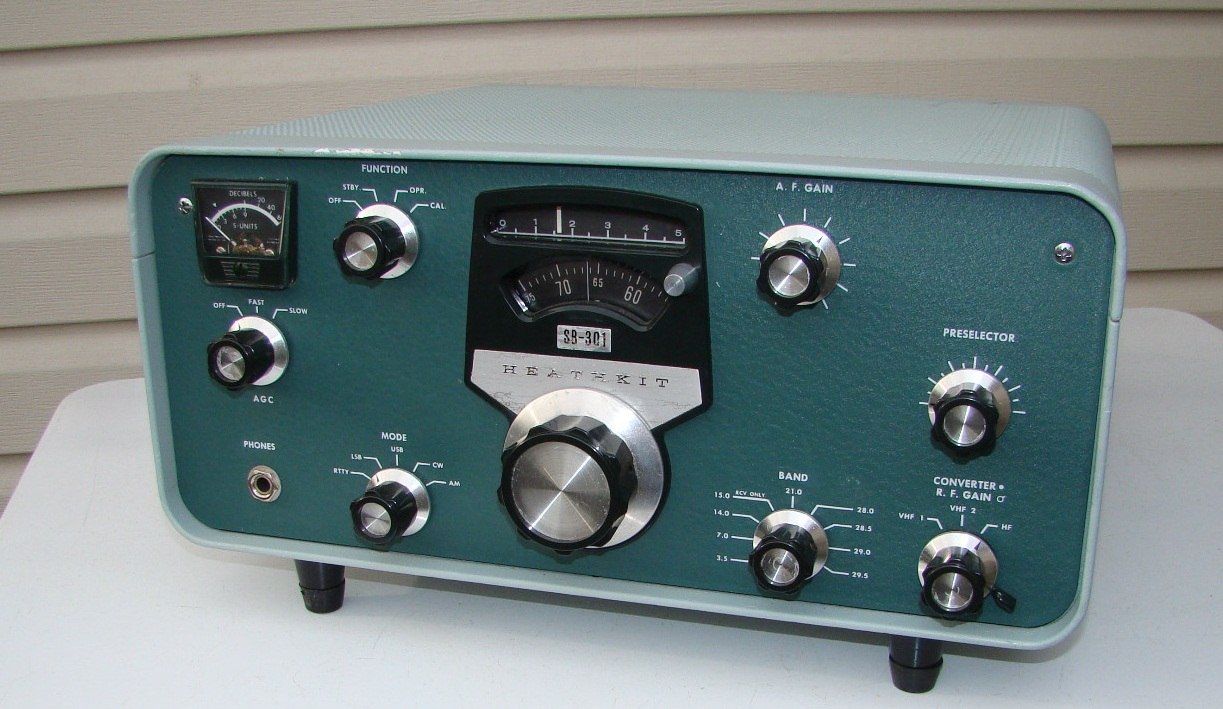 Figure 1 — An SB-301 receiver in the two-tone SB-series finish: grey wrap-around cabinet, green wrinkle panel, dark-green knobs with bright inserts. The slide-rule scale above the round dial counts hundreds o…